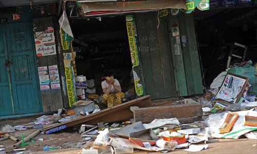 A Muslim woman sits outside her damaged shop after riots broke out in a village at Oakkan town, some 100 kilometers north of Yangon on Wednesday. One person was killed and nine injured after mobs attacked mosques and burned homes in central Myanmar, authorities said, in the latest religious unrest to erupt in the nation. Photo: AFP