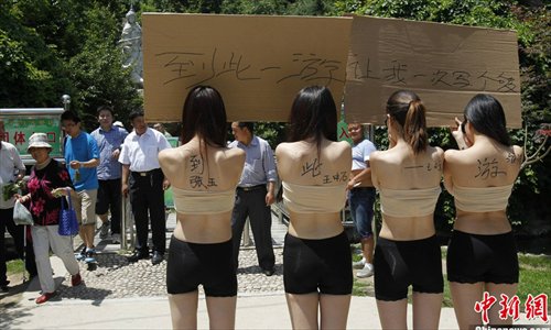 Four girls hold boards with words demanding for a special place where the tourists can sign their signitures at will in Yangzigou scenic spot, in Centeral China's Henan Province, June 2, 2013. (Source: chinanews.com)