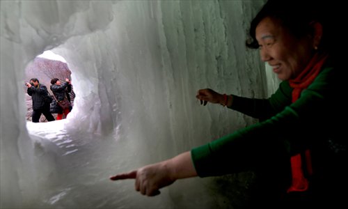 A tourist enters an ice tunnel to look at the back of the icefall in Mentougou district Saturday. The icefall is open to the public every winter. Photo: CFP  