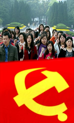 Party members from foreign companies swear an oath by a Communist Party of China flag at a cemetery for revolutionary martyrs in Shanghai on April 24. The activity was organized by the Shanghai Foreign Service Co. Photo: Xinhua