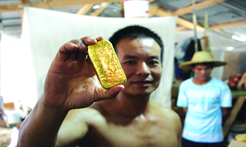 Miner Li Zengquan holds up a gold block weighing over 700 grams in a mine in Kumasi, Ghana,on November 1. Photo: IC