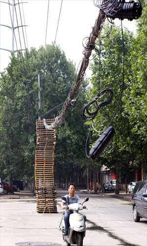 A man rides through a bunch of fallen electric cables lifted by a stack of 46 wooden frames on Xingfu Beilu in Xi'an, Shaanxi Province on Thursday. Photo: CFP