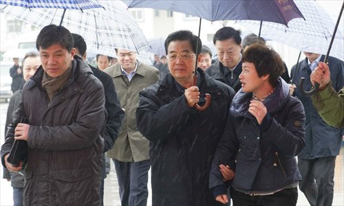 Photo released on Dec. 29, 2012 shows Chinese President Hu Jintao (C, front) holds umbrella for the Party chief of Hengbei Village as he listens to the latter's briefing in Yancheng, east China's Jiangsu Province.