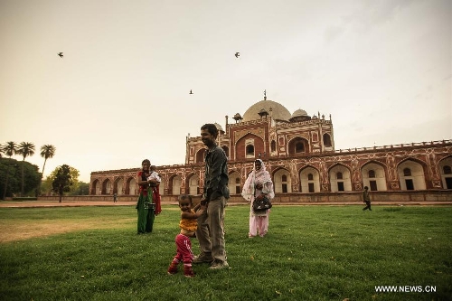 Tourists play on the lawn of Humayun's Tomb in New Delhi, capital of India, May 12, 2013. Humayun's Tomb, located in east New Delhi, was built in 1569 to 1570 by Humayun's widow. As a precursor to the Taj Mahal, it stands on a platform of 12,000 square meters and reaches a height of 47 meters. The earliest example of the Persian influence in Indian architecture, the tomb itself is in the center of a large garden, surrounded by 12 hectares of gardens with pools joined by channels. The tomb brought Persian style to Delhi, but the two-tone combination of red sandstone and white marble is local, which shows the merging of different cultures. Humayun's Tomb was inscribed on the World Heritage List by the United Nations Educational, Scientific and Cultural Organization in 1993. (Xinhua/Zheng Huansong) 