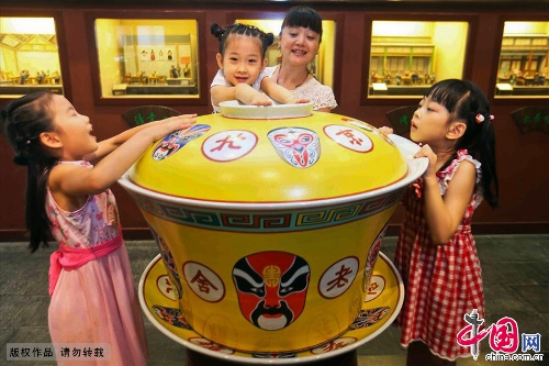 A 200kg ceramic tea bowl debuted June 30 at the Laoshe Teahouse, a world-famous Chinese folk teahouse in Beijing. The huge bowl, an enlarged version of the classical ceramic bowls with yellow lids used at the teahouse, was made by craft masters in Jingdezhen, which is known as the Porcelain Capital of China. The 75x88 cm-bowl is currently the biggest of its kind in the world. Its makers have applied to have it listed in the Guinness Book of World Records. The party at which the bowl debuted was held to mark the tenth anniversary of the death of teahouse founder Yin Shengxi. (Photo:China.org.cn)