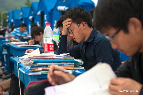 High school students study to prepare the college entrance exam this summer outside tents at a temporary settlement at the Tianquan Middle School in quake-hit Tianquan County, Ya'an City, southwest China's Sichuan Province, April 22, 2013. A 7.0-magnitude earthquake jolted Lushan County of Ya'an City in the morning on April 20. (Xinhua/Liu Jinhai)