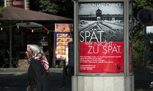 A woman walks past a placard in Berlin featuring a photograph of the Auschwitz-Birkenau death camp on Tuesday and the tag line
