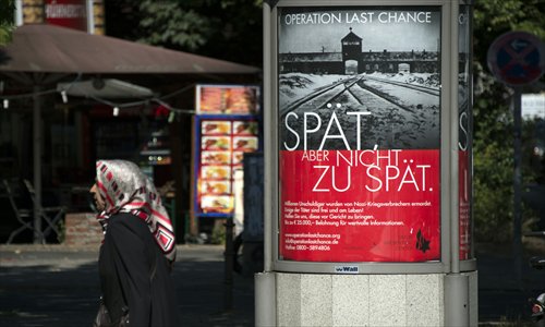 A woman walks past a placard in Berlin featuring a photograph of the Auschwitz-Birkenau death camp on Tuesday and the tag line 