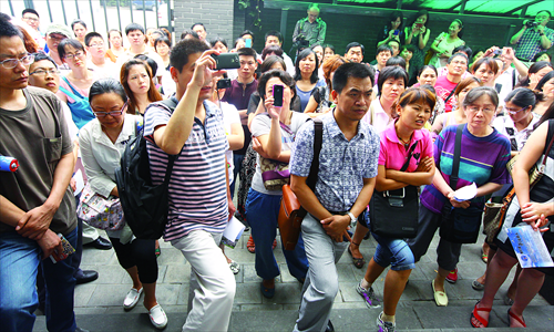 Migrant parents gather outside the office for letters and calls at the Ministry of Education Thursday morning. The parents are listening to a parent representative asking police why two of their number had been detained. Police would not give a reason. Photo: Guo Yingguang/GT