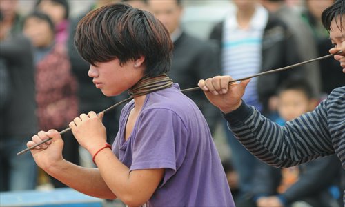 A teenager participating in a beggars' performance has a steel wire wrapped around his neck in Fangchenggang, Guangxi Zhuang Autonomous Region on Thursday sparking the curiosity among onlookers. Photo: CFP