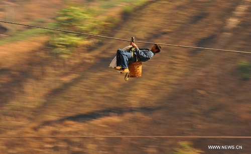 A resident from Shuangmidi Village crosses the Nujiang River via a zip-line in Liuku County of Nujiang Lisu Autonomous Prefecture, southwest China's Yunnan Province, Feb. 2, 2013. More than 98 percent of Nujiang Lisu Autonomous Prefecture is occupied by mountains and valleys. The zip-lines have been quite popular transportation method along the Nujiang River since the ancient time. However, as transport conditions improve in recent years, a growing number of traditional zip-lines along the Nujiang River Valley have been dismantled or replaced by bridges. (Xinhua/Wang Changshan)  