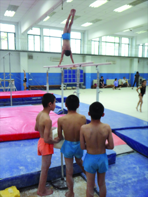 One boy practices gymnastics while others look on in Shichahai as part of a gruelling training program.
