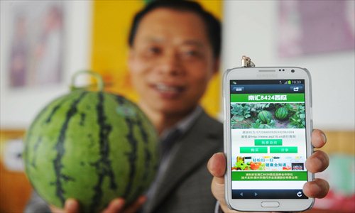 A customer holds up a local watermelon labeled with a Quick Response (QR) code, which allows consumers to scan the fruit with a smartphone app to see where it was grown. The codes aim to ensure food safety. All of the labeled watermelons come from the 8424 variety, one of the most sought-after kinds of watermelons in the city. Photo: Cai Xianmin/GT