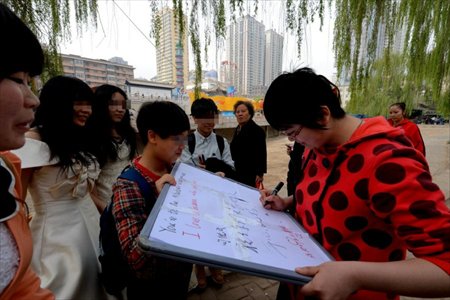 Lesbian lovers Xixi and Xiaoyu held a wedding ceremony in a park in Lanzhou, northwest China's Gansu province on April 15, 2013. Wearing wedding dress and holding a sign reading 
