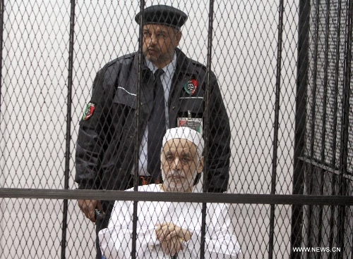 Former Libyan Prime Minister Baghdadi al-Mahmoudi (front) sits in a cage during his trial at a court in Tripoli, capital of Libya, on Jan. 14, 2013. The trial of former Prime Minister Baghdadi al-Mahmoudi started here on Monday. Mahmoudi, who served as the last prime minister in former leader Muammar Gaddafi's administration from 2006 to 2011, fled to Tunisia in September 2011 after the armed rebels seized the Libyan capital of Tripoli during the unrest. (Xinhua/Hamza Turkia) 