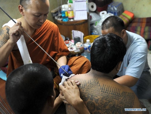 A Buddhist monk uses a needle to tattoo the shoulder of a man at Bang Phra temple in Nakhon Pathom province of Thailand, March 22, 2013. Thailand's traditional tattoo festival 