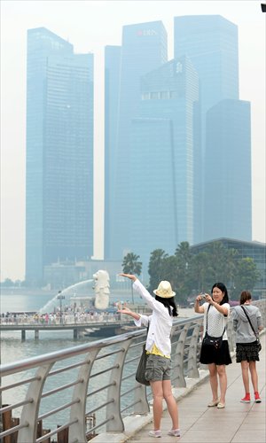 People pose for pictures in front of the Marina Bay Financial Center as it is blanketed by haze in Singapore on Monday. Air pollution from forest fires in Indonesia's Sumatra island reached severe levels in Singapore on Monday, triggering a health alert in the densely populated city-state. Photo: AFP