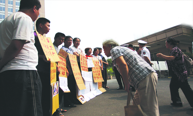 An elderly passer-by reads posters held by petitioners from Shanxi, Shandong and Henan provinces at the gate of the Ministry of Health in Beijing on June 25, 2010. The petitioners were seeking justice for their kids who were allegedly injected with defective vaccines, which caused them health problems. Photo: CFP