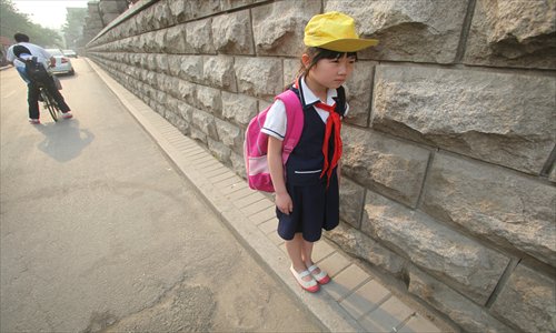 A school student walks on a pedestrian path, about 20 centimeters wide, at Yunshu Street in Ji'nan, Shandong Province on Wednesday. Around 1,000 students from a high school and a primary school must use the path every day. Photo: CFP