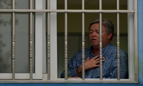 US businessman Chip Starnes stands behind the bars of his office window after being held hostage for five days over a labor dispute at his Specialty Medical Supplies factory in Huairou district, Beijing on Tuesday. Photo: AFP