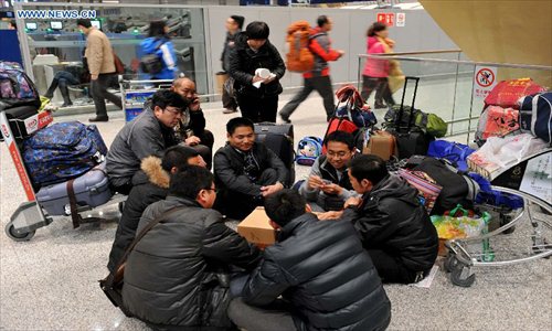 Passengers play cards together at Kunming Changshui International Airport in Kunming, capital of Southwest China's Yunnan Province, January 3, 2013. Affected by the dense fog, a total of 434 flights were cancelled and about 7,500 passengers were trapped in the airport until 9 pm Thursday.(Xinhua/Lin Yiguang)