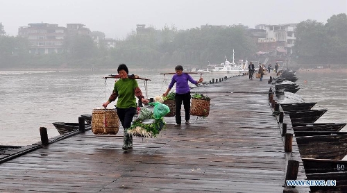 People walk on an ancient floating bridge across the Gongjiang River in Ganzhou, east China's Jiangxi Province, April 1, 2013. The wooden bridge, running 400 meters, is supported by some 100 floating boats anchored in a row. The bridge could date back to the time between 1163 and 1173 during the Song Dynasty, and has become a scene spot of the city. (Xinhua)