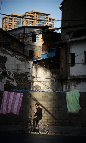 A resident cycles home under quilts hanging on washing. Photo: Cai Xianmin/GT