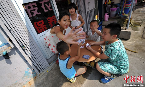 Several children play cards in an alley while their parents work. Photo: Jin Shuo/chinanews.com 