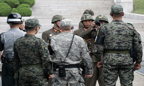 A North Korean soldier takes pictures as a US (middle) and South Korean Army soldiers stand guard after a ceremony marking the 59th anniversary of the end of the Korean War, at Panmunjom on Friday. Photo: AFP