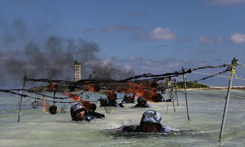 Soldiers crawl through water under flaming steel mesh as part of a military training competition held by the PLA on the Xisha Islands December 5. Photo: mil.cnr.cn