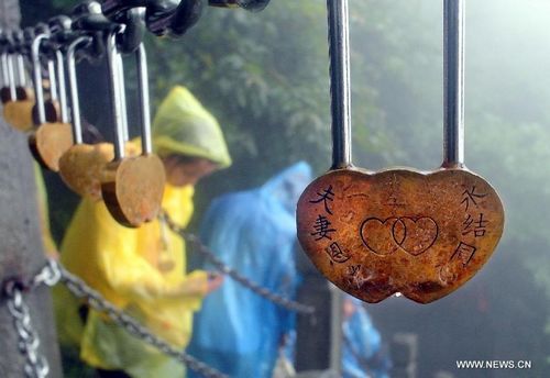 Visitors attach marital harmony locks to an iron cable on the Fanjing Mountain, a natural scenic spot as well as a Buddhist sacred land, in Tongren, Southwest China's Guizhou Province, July 25, 2012. Photo: Xinhua