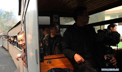 Tourists looks out of Jiayang mini steam engine train in Qianwei County, southwest China's Sichuan Province, March 15, 2012. Built in 1958, Jiayang mini steam engine train with a narrow rail gauge, used to be a coal transportation. Later, added some passengers carriages, it became the major transportation for local villagers living in and around the mountainous Bajiaogou town and Shixi town. As the steam trains disappear in the world, more and more tourists from home and abroad came here to visit the mini steam engine train. Photo: Xinhua