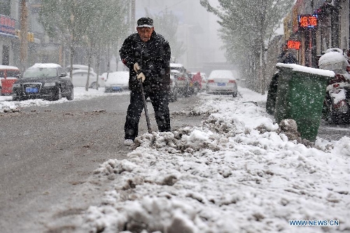 A citizen clears snow and ice on a road in Taiyuan, capital of north China's Shanxi Province, April 19, 2013. A heavy snowfall hit Shanxi's capital city on Friday, where a red alert of snowstorm was issued by local Meteorological Station. (Xinhua/Zhan Yan) 