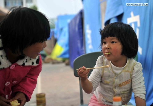 A little girl eats breakfast at a temporary settlement for quake-affected people in Lushan Middle School in Lushan County, southwest China's Sichuan Province, April 26, 2013. A 7.0-magnitude jolted Lushan County on April 20. (Xinhua/Li Wen) 