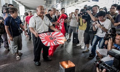 Activist Tsang Kin-shing (second left), nicknamed The Bull, burns a paper Japanese imperial military flag during a demonstration near the Japanese consulate in Hong Kong on Wednesday. Photo: AFP
