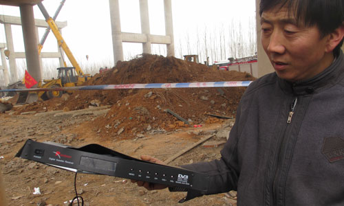 Liu Erzeng, a nearby resident, holds a distorted digital satellite receiver that fell from a collapsed bridge in Sanmenxia, Henan Province on Saturday. Photo: Yan Shuang /GT