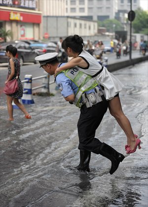 A traffic police officer carries a woman on his back crossing a road flooded due to exploded water pipes in Hangzhou, Zhejiang Province on Tuesday. Web users have teased the officer as being way too 
