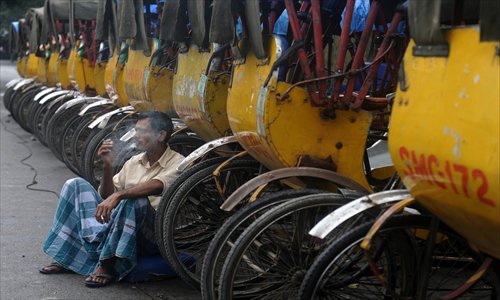 An rickshaw puller, sitting beside a row of parked rickshaws, smokes a leaf cigarette during a general nationwide strike in Siliguri, northeastern India, on Thursday. Photo: AFP 