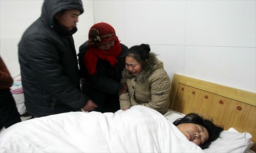 Surrounded by her family and friends, Yuan Lihai, the foster mother, lies on a sickbed at the People's Hospital in Lankao, Central China's Henan Province on Sunday morning. Photo: CFP