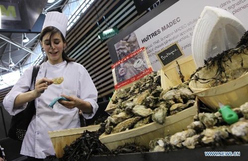 A woman prys an oyster at the International Hospitality and Food Service Fair (SIRHA) in Lyon, France, on Jan. 30, 2013. The five-day fair was closed on Wednesday. The biyearly SIRHA was founded in 1984 and is considered one of the most influential food expos in Europe. (Xinhua/Gao Jing)