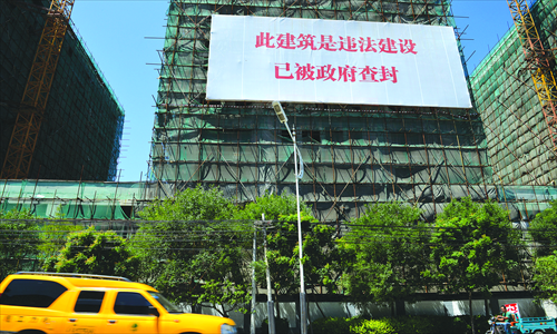 A banner hangs on buildings still under construction, indicating that they are limited rights properties and are slated for demolition, in Tongzhou, Beijing, on July 16.