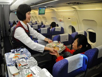 A stewardess serves passengers on the test flight to the Daochengyading Airport in Daocheng County of the Tibetan Autonomous Prefecture of Garze, southwest China's Sichuan Province, November 23, 2012. The first test flight of the airport successfully landed Friday. With the height of 4,411 meters above sea level, the Daochengyading Airport becomes the highest civil airport in the world. (Xinhua/Xue Yubin)