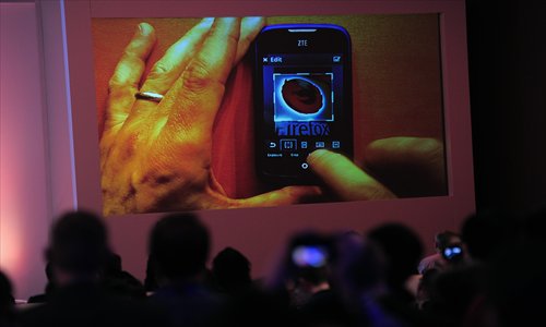 People watch a screen displaying a ZTE mobile phone showing a Firefox logo during a press conference to present the new Firefox OS mobile operating system in Barcelona on Sunday, a day before the start of the 2013 Mobile World Congress. The mobile fair opened Monday and runs through Thursday. Photo: IC