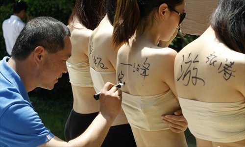 Four girls hold boards with words demanding for a special place where the tourists can sign their signitures at will in Yangzigou scenic spot, in Centeral China's Henan Province, June 2, 2013. (Source: chinanews.com)
