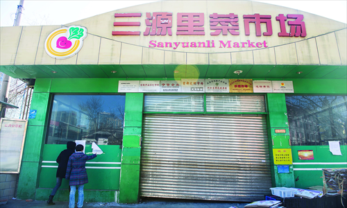 People read the closure notice at the entrance to the Sanyuanli vegetable market in Chaoyang district. It is closed for a 45-day renovation. Photo: Li Hao/GT