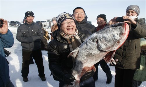 A tourist holds up a fish during the 8th winter fishing festival at the Wulungu Lake, the Xinjiang Uyghur Autonomous Region, Saturday. The annual cultural festival has become a famous tourism experience, reeling in around 22,000 people from across the country. Photo: CFP