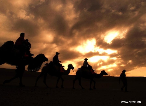 &nbsp; Tourists ride on camels visiting the scenic spot of the Mingsha Mountain and Crescent Spring in Dunhuang City, northwest China's Gansu Province, May 21, 2013. Dunhuang has received about 749,200 tourists in the first four months of 2013, increasing 58.63 percent year on year. (Xinhua/Nie Jianjiang)&nbsp; 