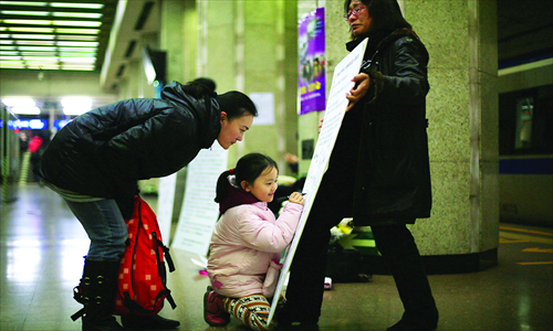 A girl signs a petition at Gulou Station on Subway Line 2 on November 23. Meng Zhaohong started collecting signatures from passengers on the birthday of her son, who was electrocuted at the station 2 years ago. Photo: CFP