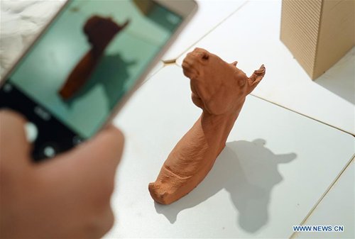A visitor takes photo of a pottery craftwork made by 3D printer in Jingdezhen, east China's Jiangxi Province, Oct. 19, 2016. (Photo/Xinhua)