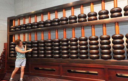 A woman stands before a giant abacus at the China Abacus Museum in East China's Jiangsu Province in August. Photo: IC